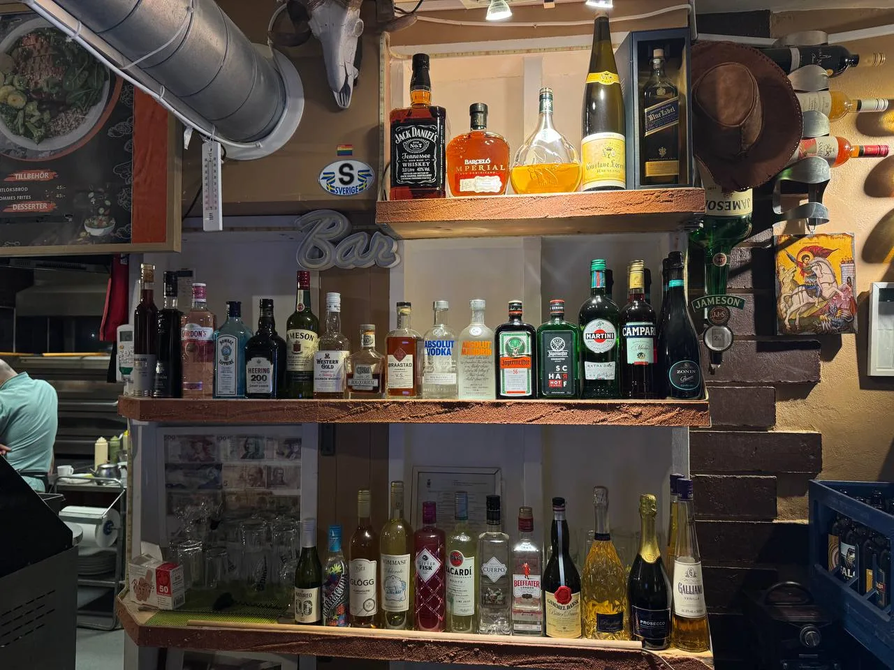Barhyllan med spritflaskor och prydnader på väggen